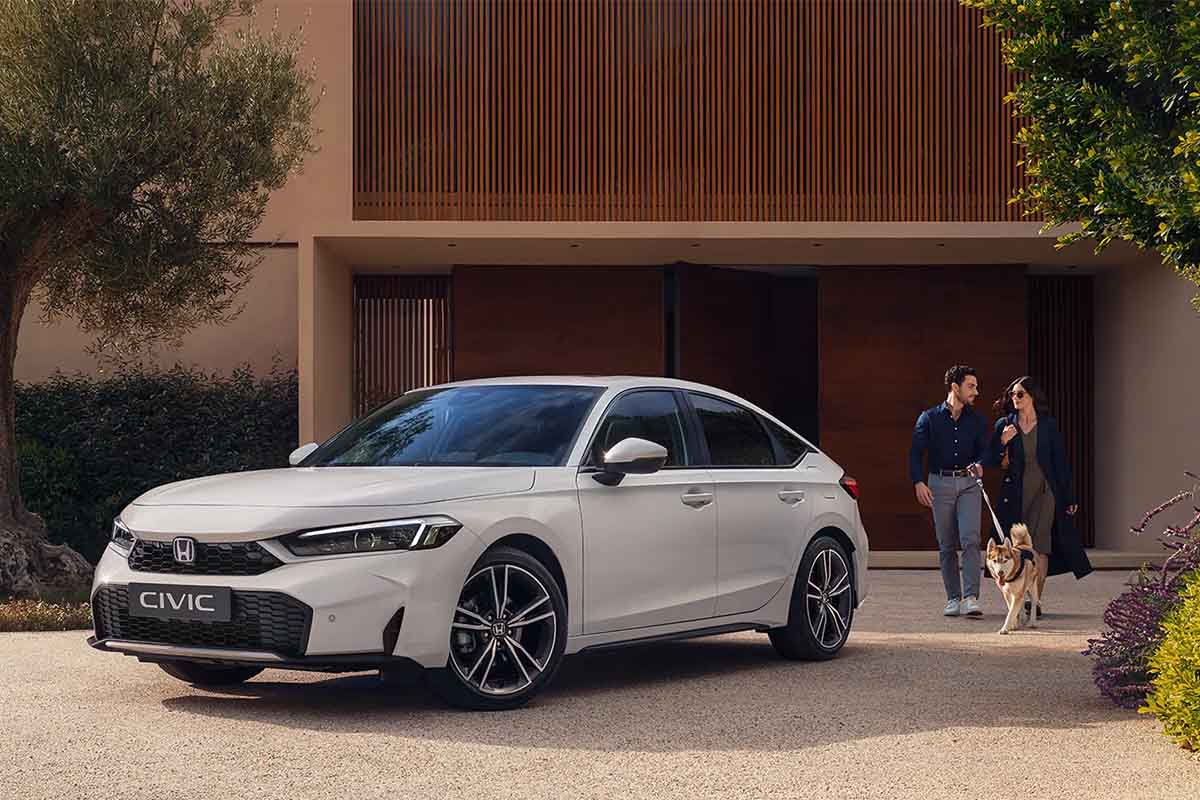 zu sehen ist ein weißer Honda Civic. daneben steht ein Paar mit Hund